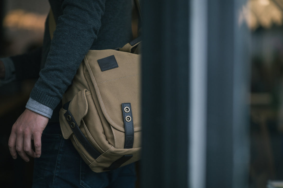 Close-up of a tan Millican bag worn over the shoulder