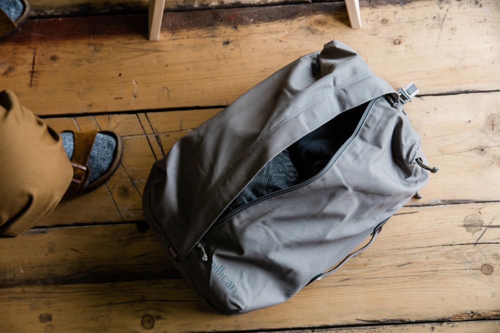 Grey Millican bag on wooden floor.