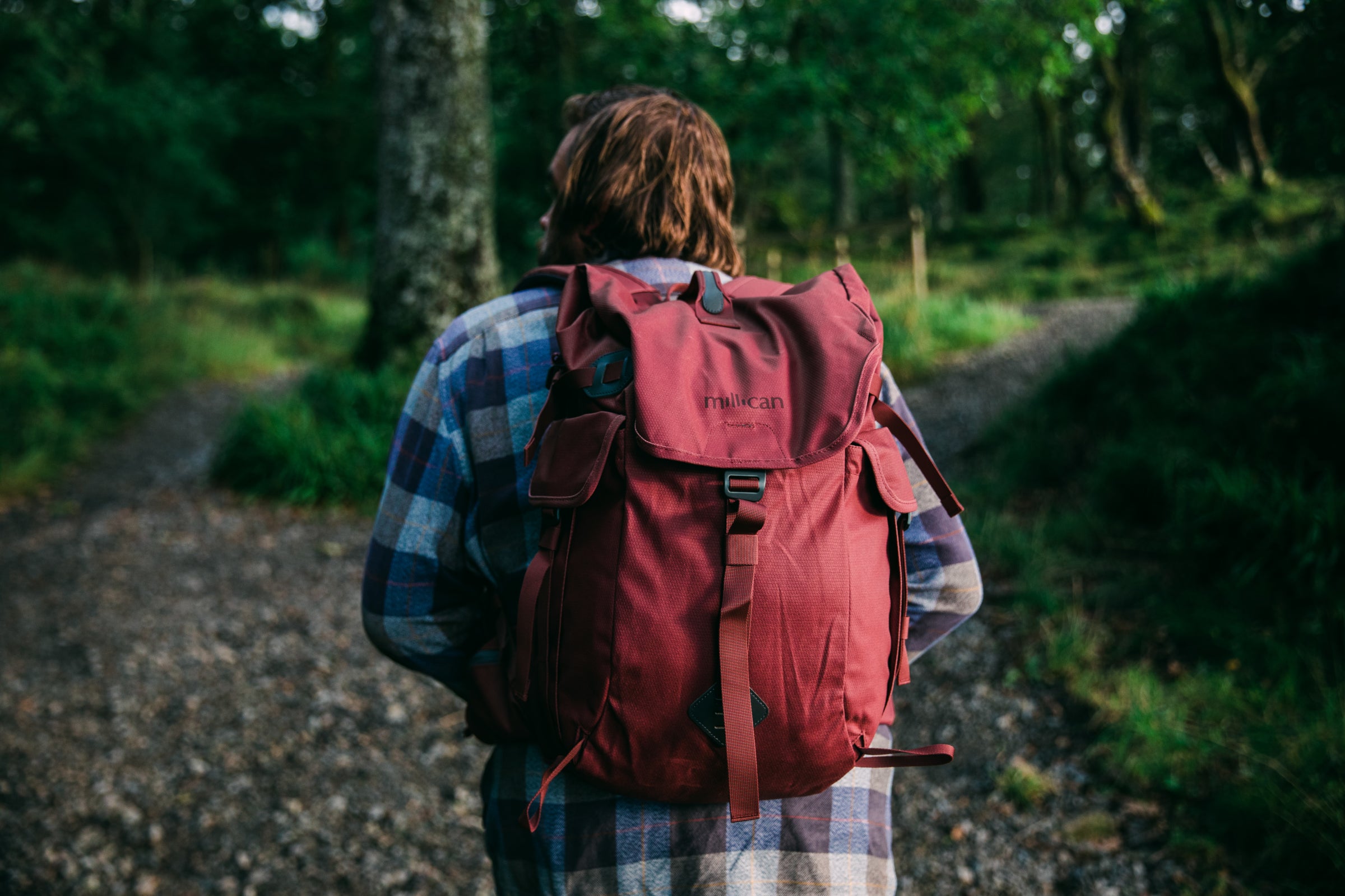 Person with a red backpack walking through a forest